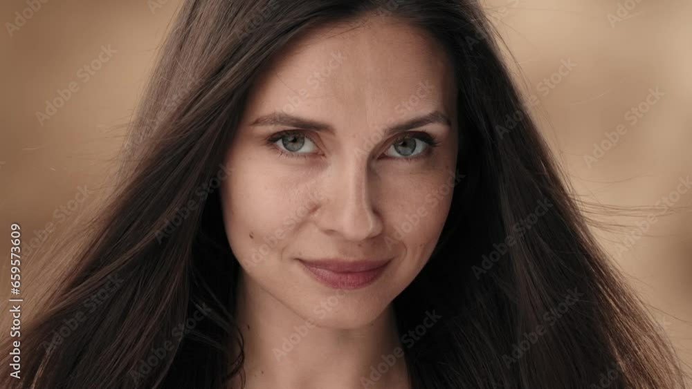 There is a close up middle aged woman in the frame against a stained background. She looks down with her head tilted, the wind blowing her hair. Then she stares intently into the camera and smiles There is a close up middle aged woman in the frame against a stained background. She looks down with her head tilted, the wind blowing her hair. Then she stares intently into the camera and smiles