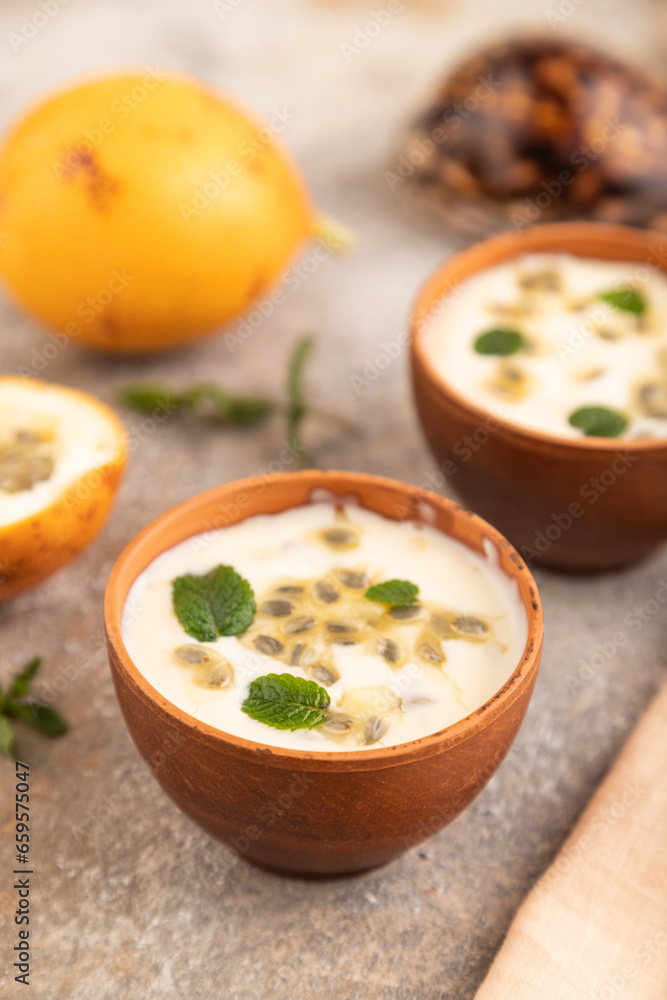 Yoghurt with granadilla and mint in clay bowl on brown concrete, side view, selective focus Yoghurt with granadilla and mint in clay bowl on brown concrete, side view, selective focus