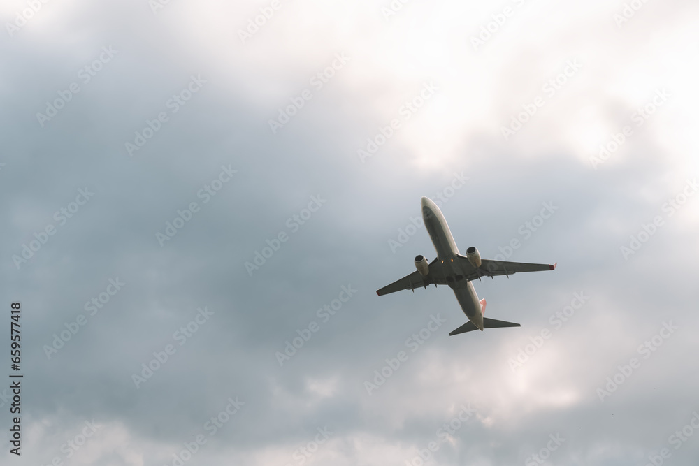 Close-up of a white passenger plane taking off against a gray overcast sky. Travel by air