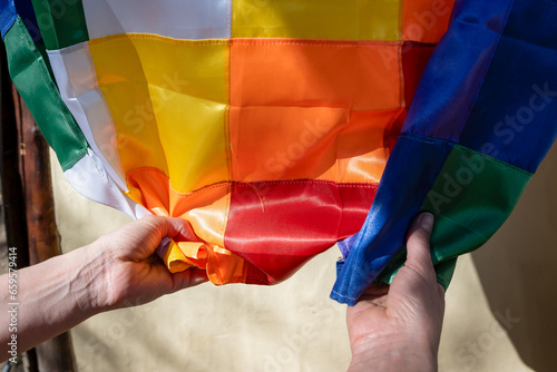 Close-up image of woman's hands clutching a silk Wiphala flag, a symbol commonly used to represent the native peoples of the Andes. photo