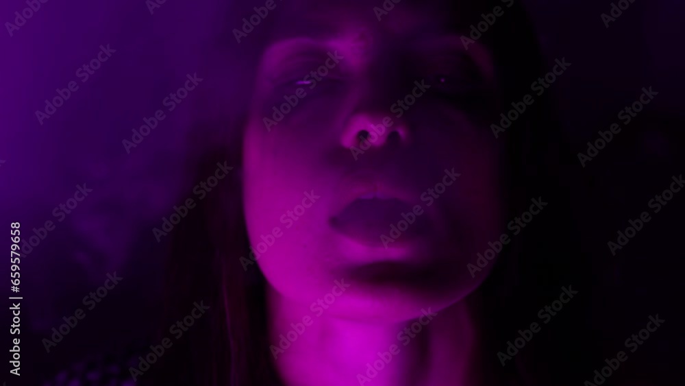 woman drug addict in neon light exhales smoke. woman drug addict in neon light exhales smoke.