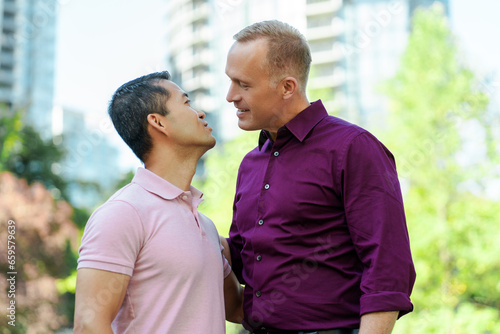 Portrait of romantic smiling homosexual couple, two gay men kissing standing in urban street