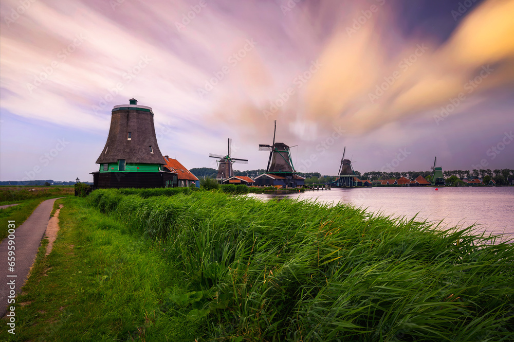 Sunset above historic farm houses and windmills in the holland village of Zaanse Schans near Amsterdam in the Netherlands.