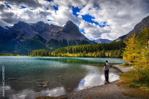 Hiker enjoys the view of Rundle Forebay Reservoir in Canmore, Canada, with Rundle Mountain in the background. photo