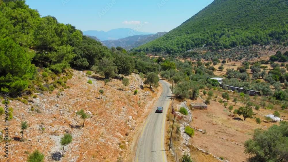 Drone follows car driving along rural road into gorge of mountains with buildings, houses and trees in Turkey. Agricultural land at foot of mountains. Hot sunny day, romance Traveling car on vacation. Drone follows car driving along rural road into gorge of mountains with buildings, houses and trees in Turkey. Agricultural land at foot of mountains. Hot sunny day, romance Traveling car on vacation.