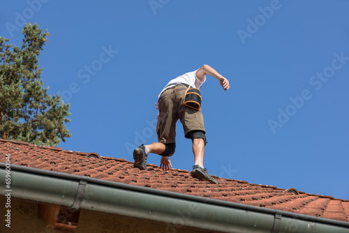 A worker prepares the roof for the installation of solar panelss. the roof of a family house with red tiles,