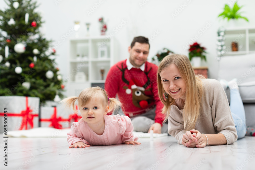 The happy family stays in a room near a decorated Christmas tree and presents The happy family stays in a room near a decorated Christmas tree and presents