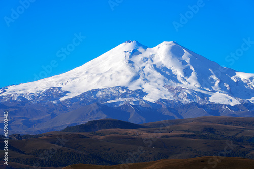 Snow-covered summit of Mount Elbrus against the blue sky. Shooting with a long lens.