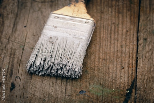 Brush covered with paint on a wooden background