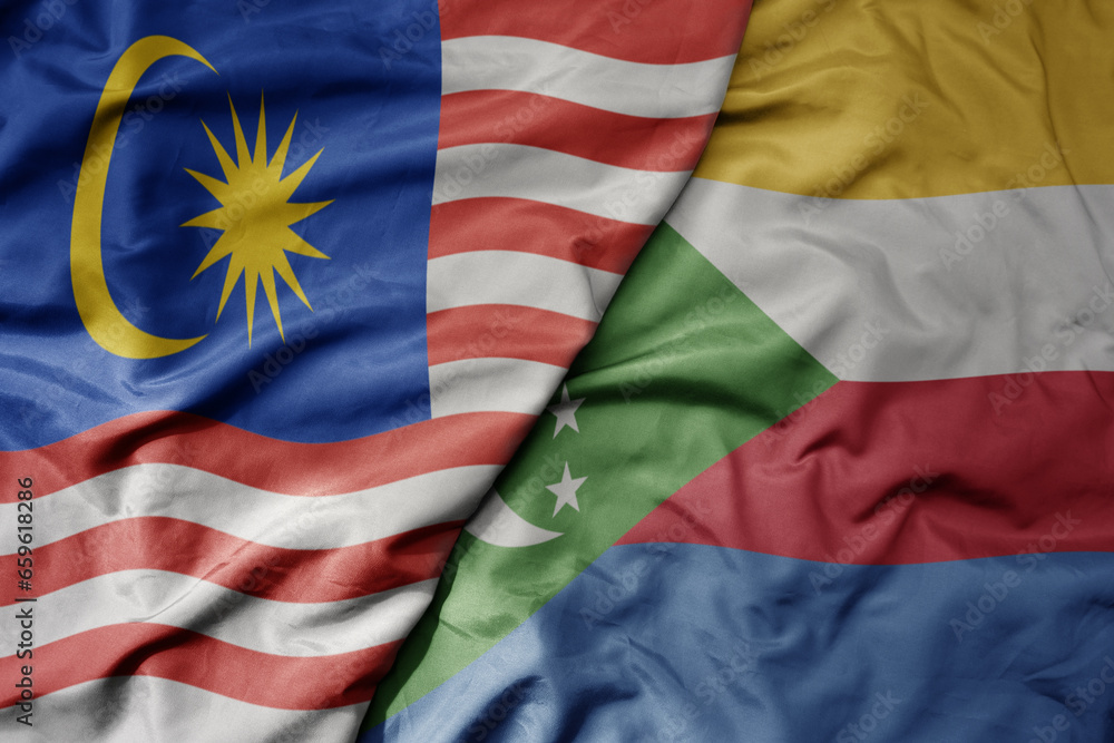 big waving realistic national colorful flag of malaysia and national flag of comoros .