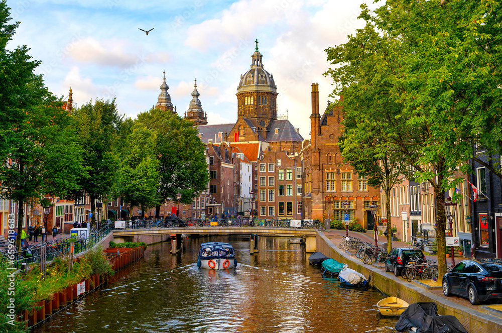 Obraz premium Amsterdam with a canal, bridges and boats. Beautiful old buildings around.