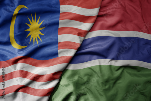 big waving realistic national colorful flag of malaysia and national flag of gambia .