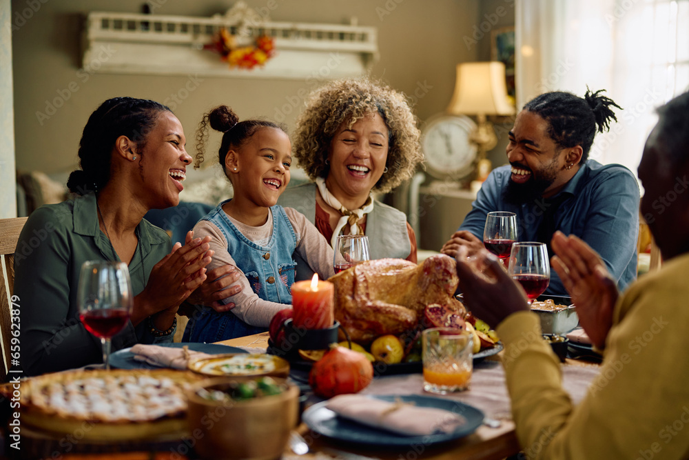 Cheerful multigeneration family has fun during Thanksgiving dinner at dining table.