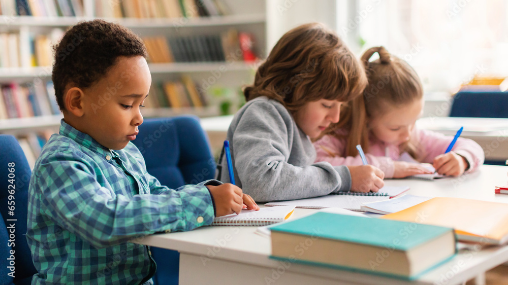 Diverse primary school children writing in copybooks during a test Diverse primary school children writing in copybooks during a test