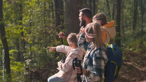 Smiling family of four enjoying hiking in trough forest.