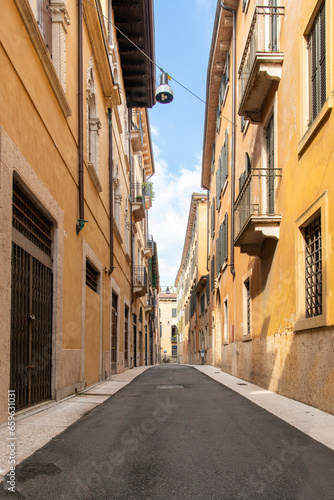 Low angle view down a typical historic narrow street in an Italian city with yellow plastered walls and high enough to provide shade in warm sunny summers