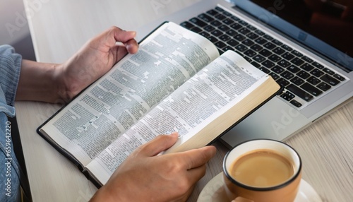 to understand the Bible in order to pray to God and to ask God to protect himself and his family. Online bible, Hands holding a cup of coffee and a bible placed on a laptop were opened for learning