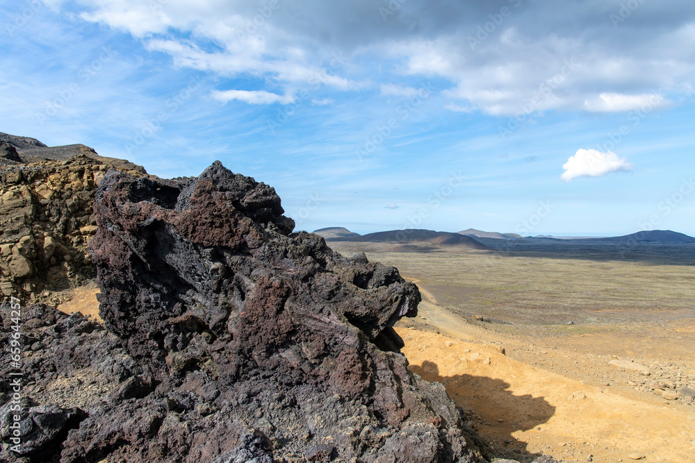 Big chunk of lava rock with in background panoramic view over volcanic landscape on Reykjanes Peninsula, Iceland, near sites of 2021 and 2022 eruptions near mountain Fagradalsfjall volcano area