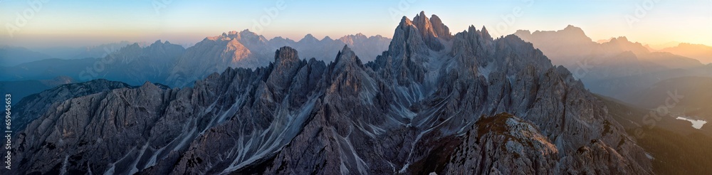 Panoramic view from Tre Cime di Lavaredo of the illuminated peaks of the Cime Eotvos mountain massif, with the three thousanders Punta Sorapis and Antelao in the background, Dolomites, Italy.  - obrazy, fototapety, plakaty 