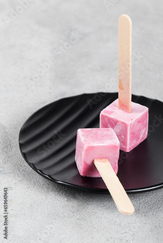 Raspberry ice cream mini cubes on a stick. On a plate. Close up. Copy space 