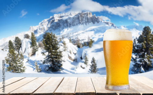 glass of beer on wooden table against winter landscape