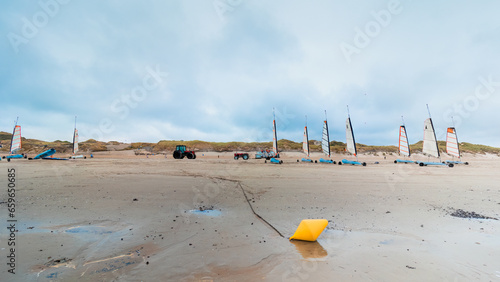 Storage of sand yachts on a beach at low tide. In winter between coast and sand a yellow buoy in the foreground. Coastline of Upper Normandy, France