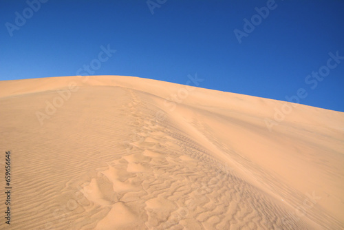 A desert sand dune against a bright blue sky. Hot climate and dehydration