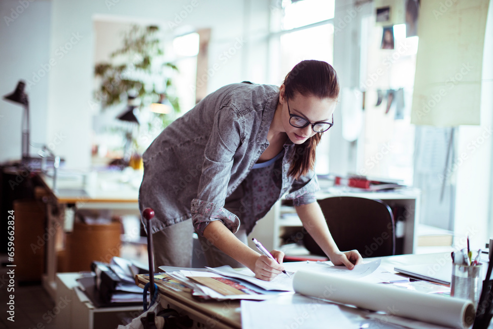 Young female architect working on building designs in the office Young female architect working on building designs in the office