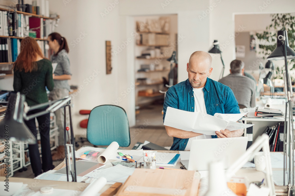 Middle aged Caucasian architect working on building plans in a modern company office Middle aged Caucasian architect working on building plans in a modern company office