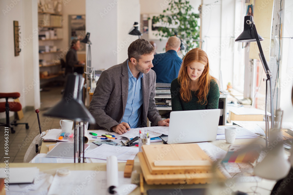 Young man and woman using the laptop while working together on a project in a startup company office Young man and woman using the laptop while working together on a project in a startup company office