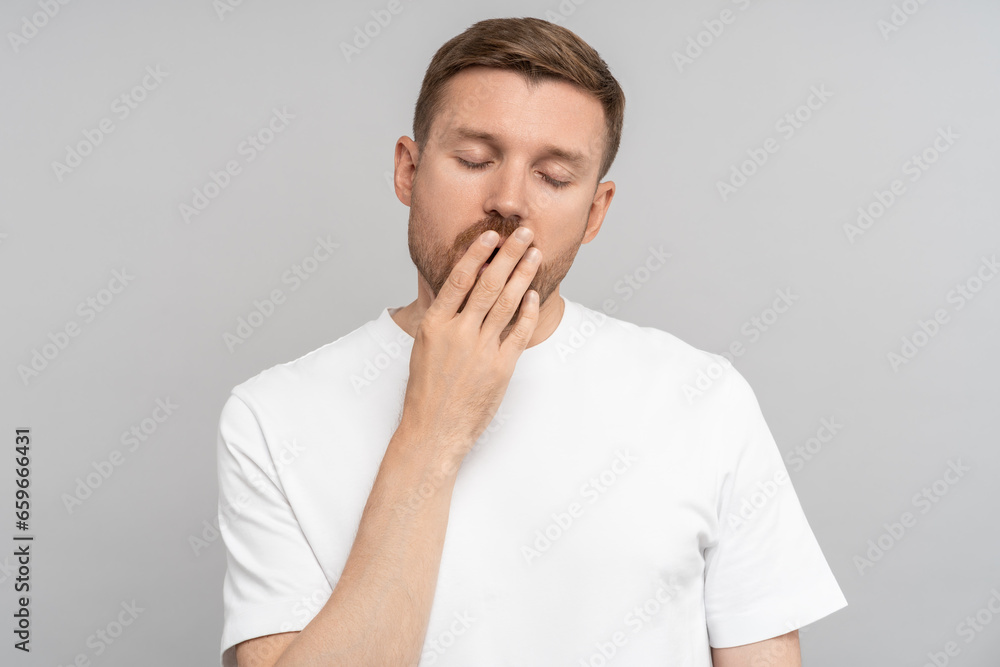 Man yawns covered with hand wants to sleep. Middle aged guy closed eyes, covered mouth with palm isolated studio background. Fatigue, tired, overworked, needed in good sound healthy sleep and rest. Man yawns covered with hand wants to sleep. Middle aged guy closed eyes, covered mouth with palm isolated studio background. Fatigue, tired, overworked, needed in good sound healthy sleep and rest.
