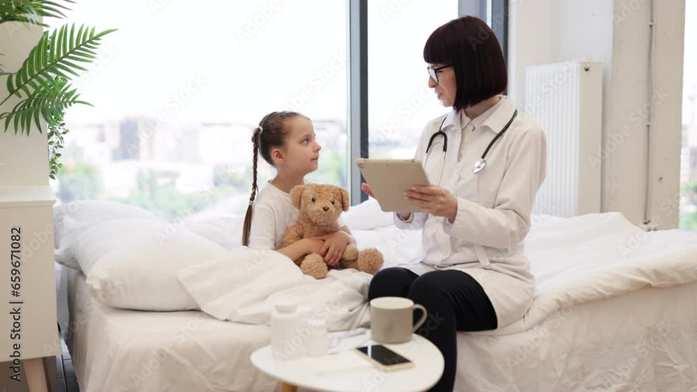 Competent female pediatrician prescribing medicine on modern tablet for sick child in spacious bedroom. Smiling girl holding teddy bear and preparing for intensive treatment at home. Competent female pediatrician prescribing medicine on modern tablet for sick child in spacious bedroom. Smiling girl holding teddy bear and preparing for intensive treatment at home.
