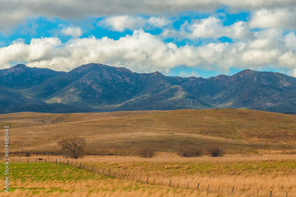 Fototapeta premium Road trippin through the dry countryside under a blue sky with clouds