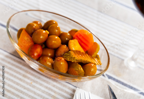 Large green olives on platter with pickled onions, garlic, carrots and cucumbers..