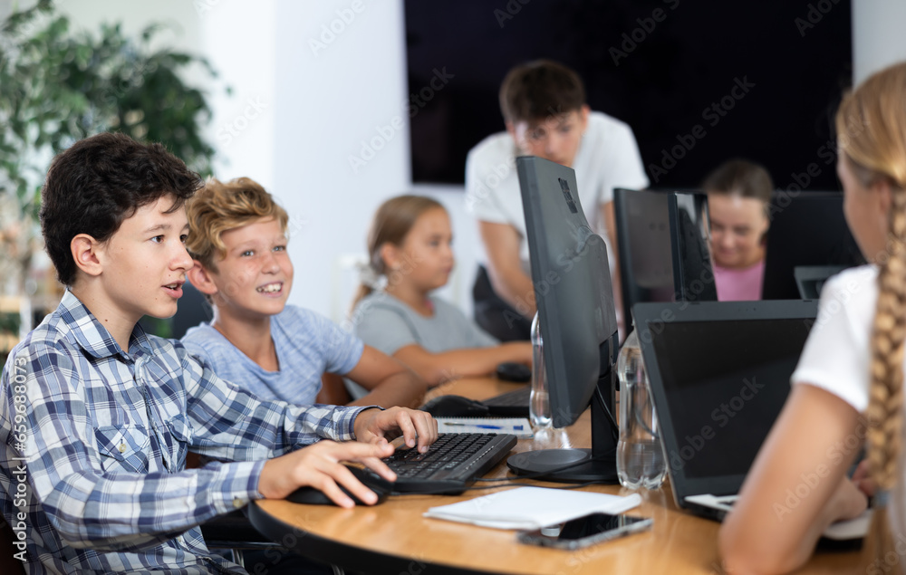 Interested preteen boys working on computer together during IT courses for children
