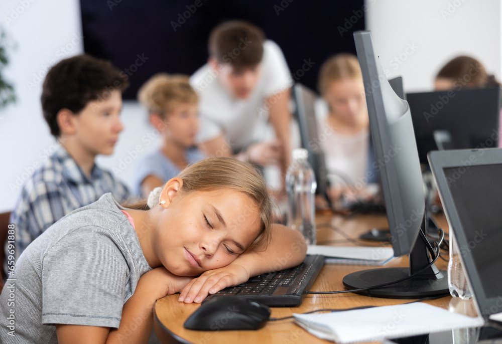 Fototapeta premium Sleepy underage girl sitting at computer table during IT courses for children