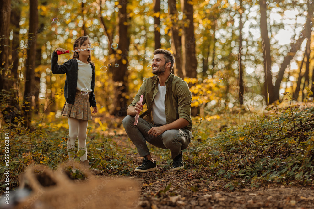 Father blowing bubbles with his daughter in a forest