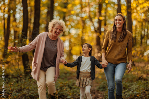 Mother, daughter and grandmother walking in the forest during autumn