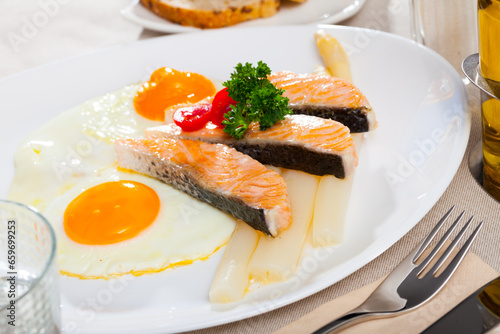 Delicious breakfast. Over easy fried eggs with salmon steaks and baked white asparagus