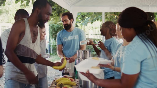 Voluntary individuals selflessly distribute free food to the needy, showing compassion and support in humanitarian charity event. Friendly volunteers offering hot meals and nourishments to the poor. photo