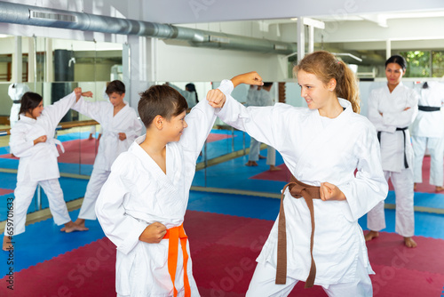 Young children sparring in pairs to practice new moves in karate class