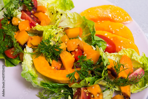 Lettuce, pumpkin, cherry tomatoes, sesame put on a plate. Served with olive oil sauce, salt, pepper, lemon and pumpkin puree