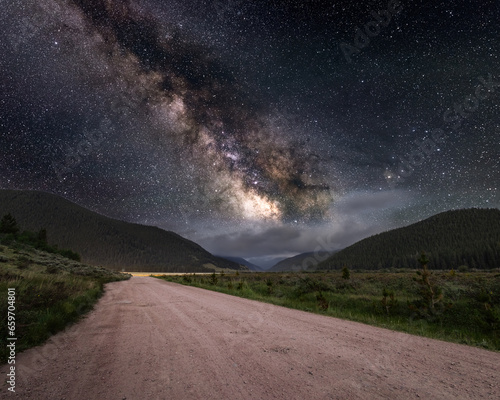 Milky way galaxy leading down to mountain valley with low clouds, Park County, Colorado