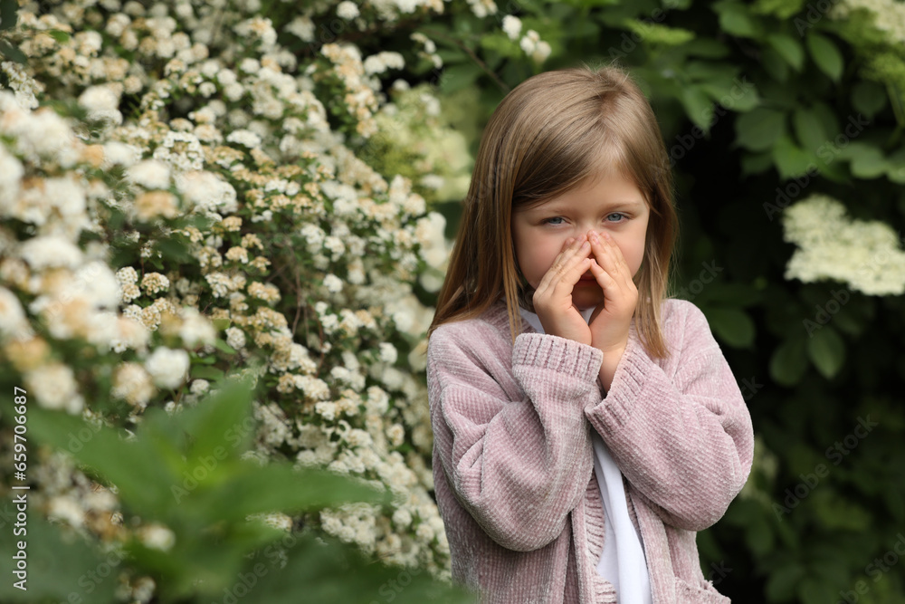 Little girl suffering from seasonal pollen allergy near blossoming tree on spring day Little girl suffering from seasonal pollen allergy near blossoming tree on spring day