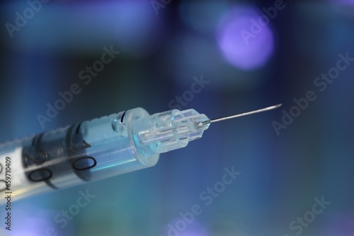 Syringe with medicine against blurred background, closeup