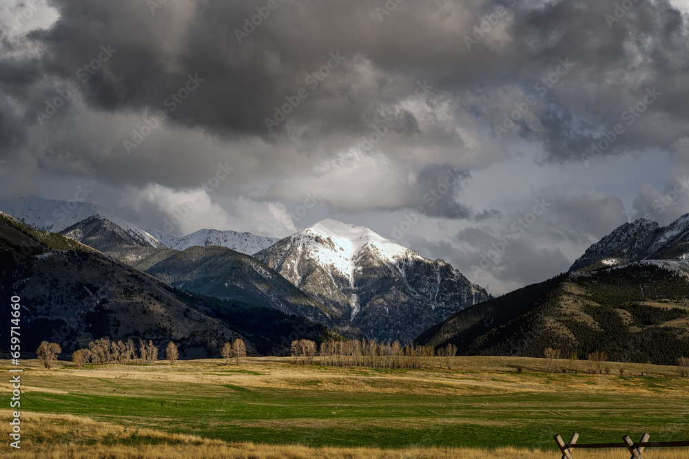 2021-03-09 OPEN LAND AND A SNOW COVERED MOUNTAIN OF THE ABSAROKA RANGE IN PRAY MONTANA WITH STORMY CLOUDS