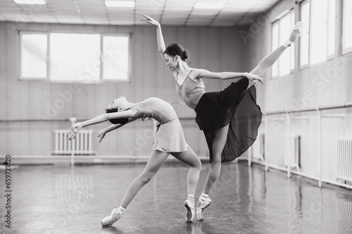 Two Asian ballerinas are dancing in the class. Monochrome. 