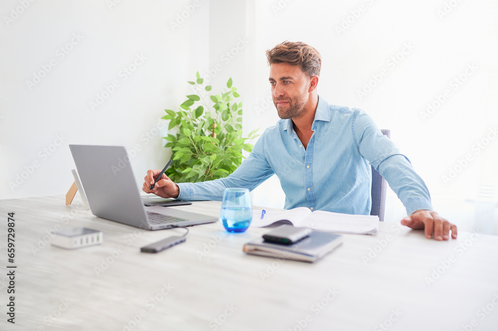 Smiling young confident man dressed in blue working with a computer at his workplace in the office. Happiness at work concept. Smiling young confident man dressed in blue working with a computer at his workplace in the office. Happiness at work concept.