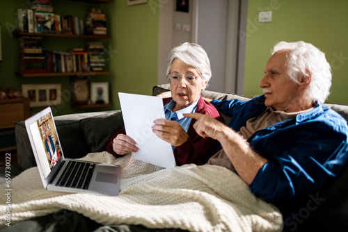 Senior Caucasian couple consulting their financial adviser on a video call on the laptop at home photo