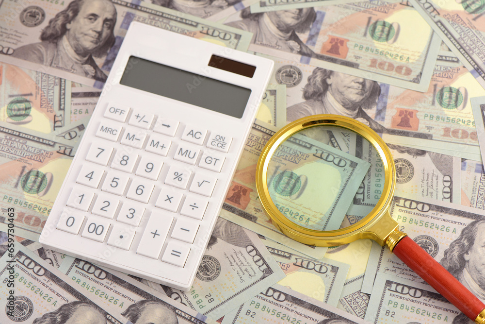 There are calculators and magnifying glasses on the props of US dollar bills There are calculators and magnifying glasses on the props of US dollar bills